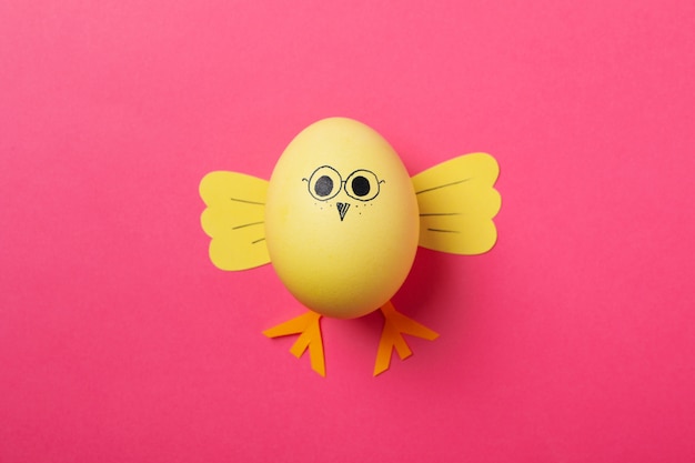Photo yellow chick made of egg on pink surface