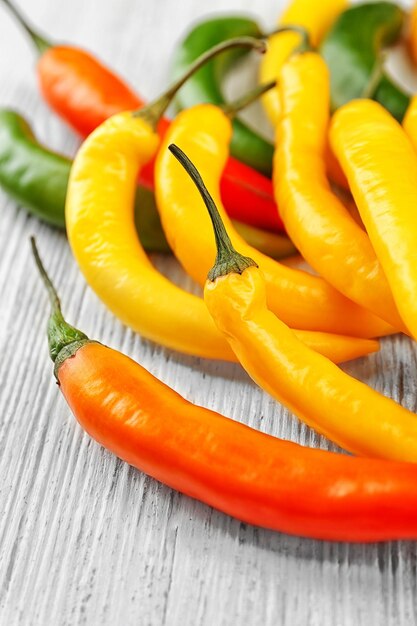 Yellow chili peppers on light wooden background