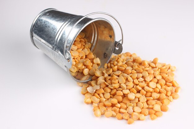 Yellow chopped peas in a bucket on a white surface