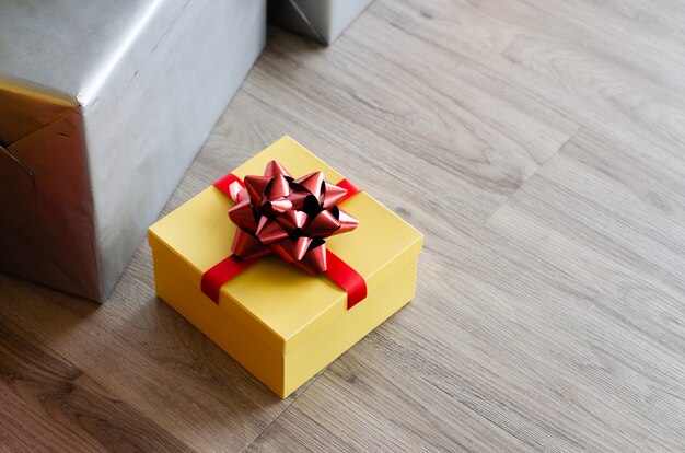 Yellow Christmas gift box  with red ribbon and copyspace for your greeting or wishes