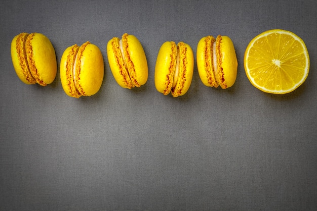 Photo yellow citrus macaroons and a slice of a fresh cut lemon on a grey background