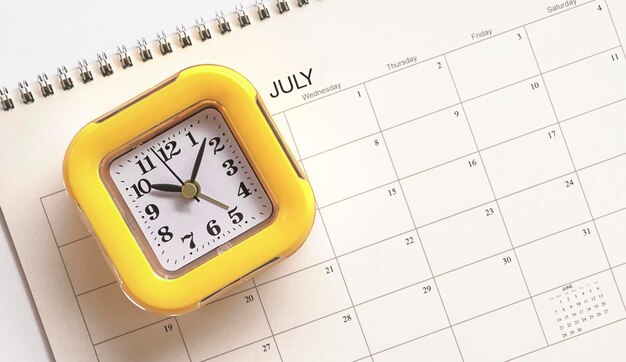 Photo yellow clock on top of calendar