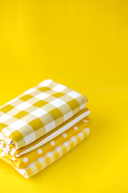 Yellow cloth with various motifs stacked on a yellow background with copy space