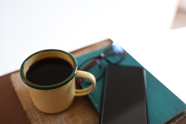 Yellow coffee mugs, phones and books on the wooden table inside the house.