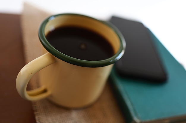 Yellow coffee mugs, phones and books on the wooden table inside the house.