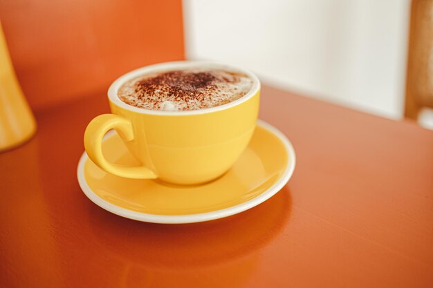 Yellow coffee mugs on wooden table in cafe