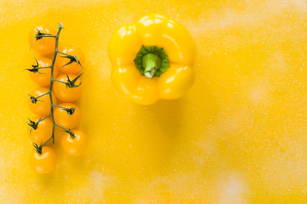 Foto colore di sfondo giallo vegetale giallo ciliegio pomodori e pepe ad alto angolo