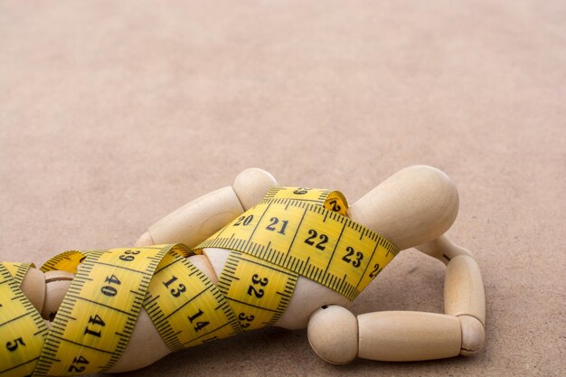 Yellow color measuring tape wrapped on wooden man