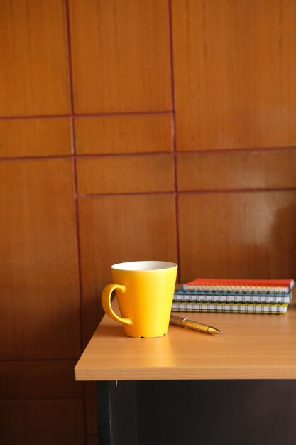 yellow color mug mockup with with notebooks on table