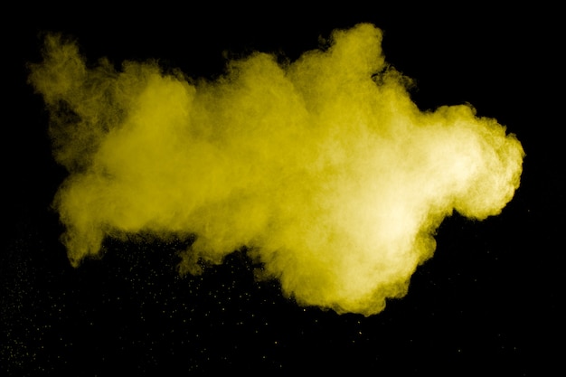 Photo yellow color powder explosion on black background.