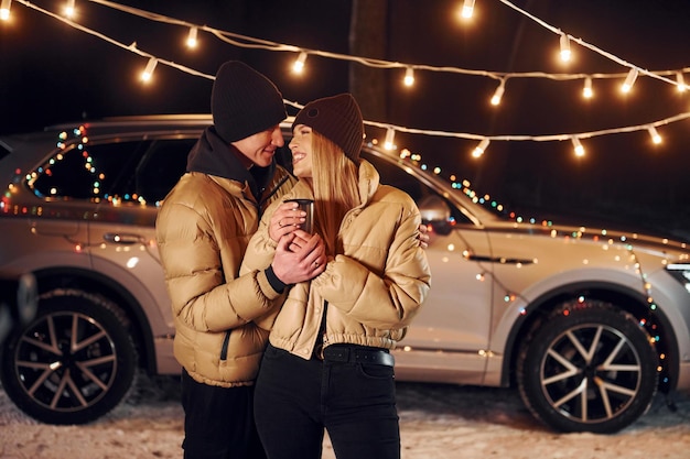 Yellow colored lighting Couple standing in the forest and celebrating New year