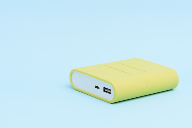 A yellow colored portable power bank isolated on light blue background.