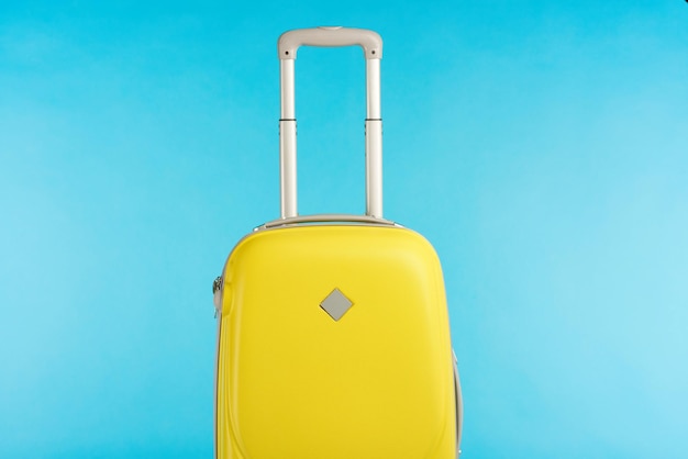 Yellow colorful travel bag with handle isolated on blue