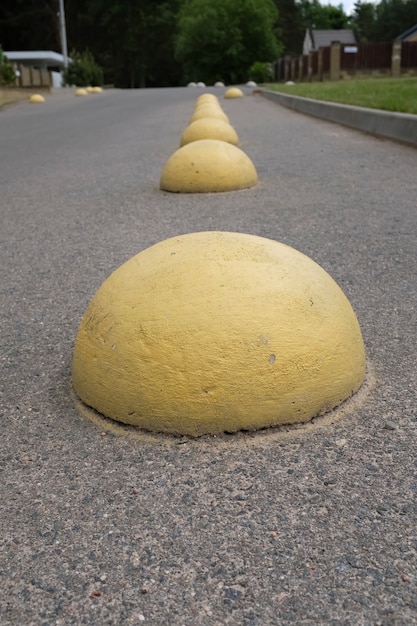 Yellow concrete hemispheres on the parking lot near the retail supermarket so that cars do not park in this place. Artificial obstacle for driving and parking. Anti-parking barrier. High quality photo