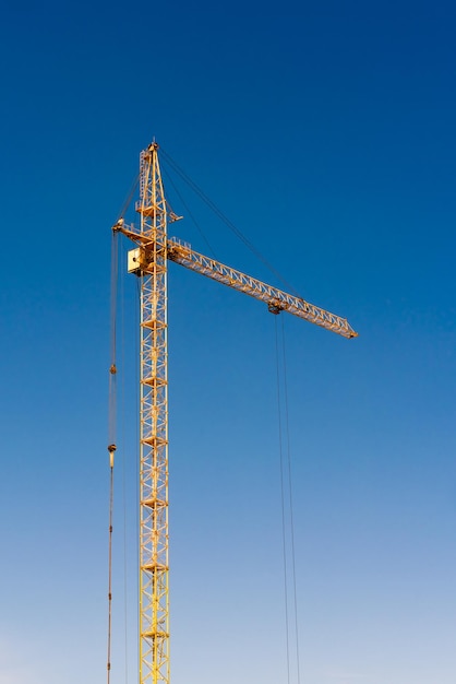 Yellow construction crane on a background of blue sky