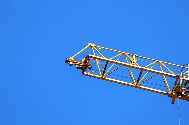 Желтый строительный кран работает, голубое небо фон фото