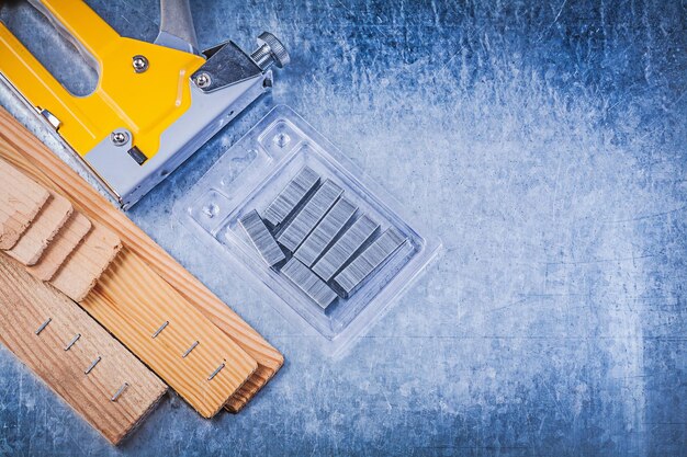 Photo yellow construction stapler metal staples wooden building board on metallic background