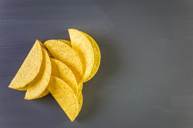 Yellow corn taco shells on a gray background.