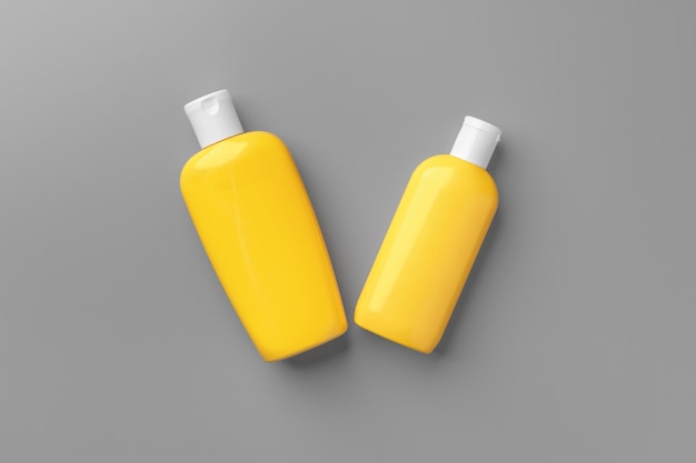 Yellow cosmetic container on gray background flat lay