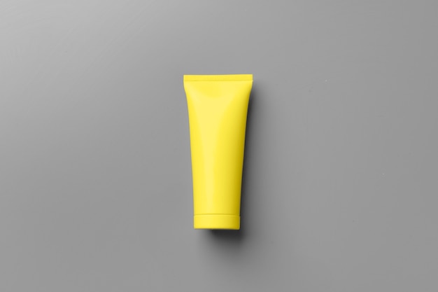 Yellow cosmetic container on gray background top view