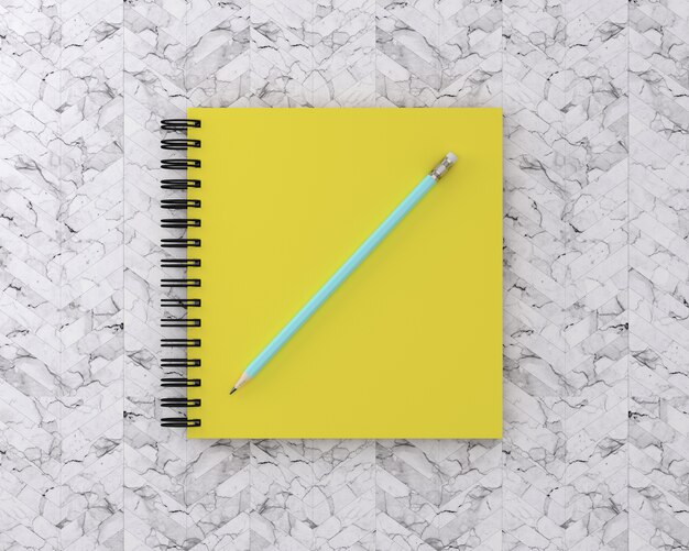 Yellow cover notebook with blue pencil on marble background. Minimal work space. 