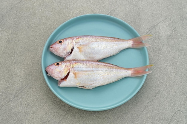 Yellow Croaker Fish Ikan Ekor Kuning geserveerd op blauw bord met kruiden en citroen Geselecteerde focus