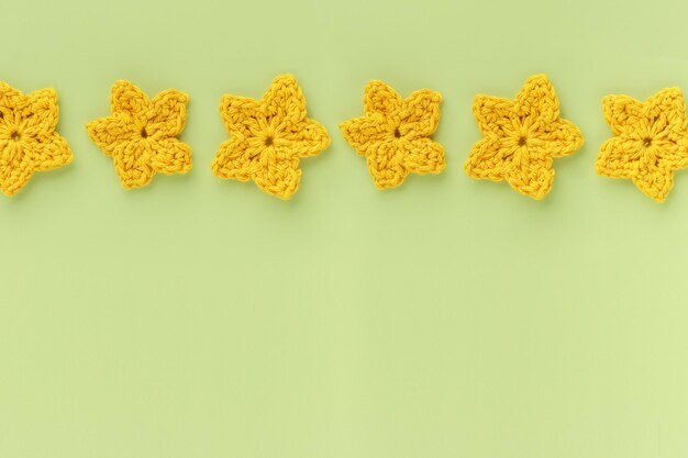 Yellow crocheted flowers row pattern on a green background