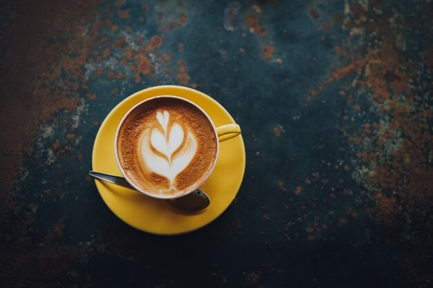 yellow cup of coffee latte art in coffee shop cafe