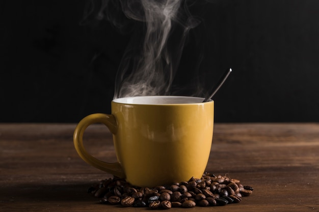 Tazza gialla con cucchiaio e chicchi di caffè