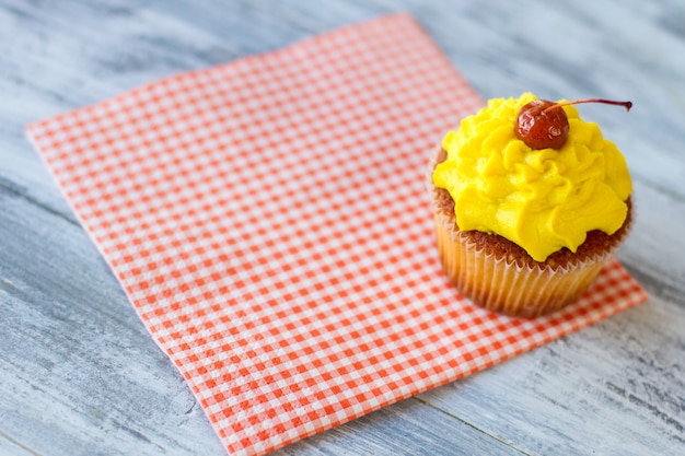 Yellow cupcake on a napkin red cherry on icing dessert served at the diner how to lift mood