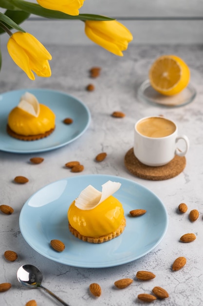 Yellow cupcakes and cup of coffee with yellow tulips on concrete background Tasty morning dessert