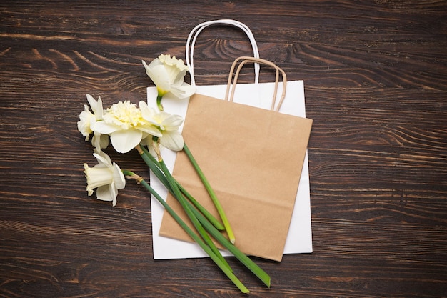 Fiori gialli del narciso e sacchetto di carta sulla vista superiore del fondo di legno