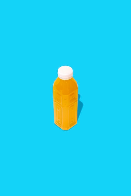 Фото Желтый детокс-сок в бутылке на синем фоне.