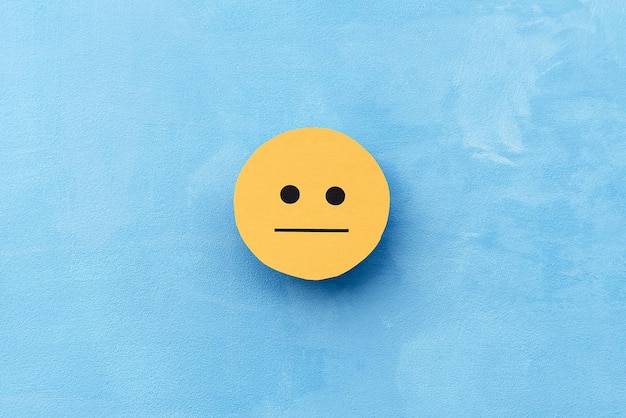 Yellow discreet face on a blue background The concept of mood selection and customer feedback Copy space business and emotions Mental health