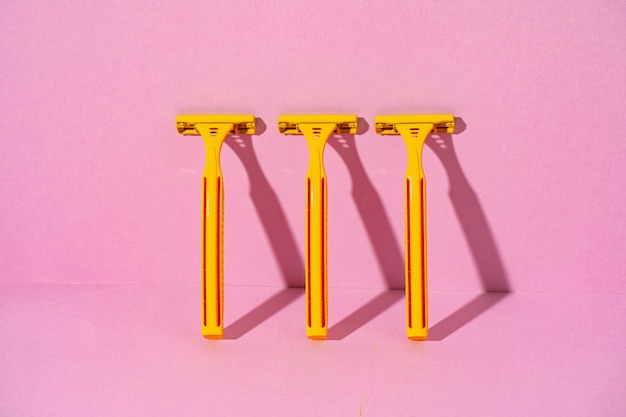 Yellow disposable razors on pink background