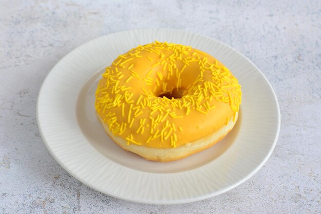 Yellow donut with sugar sparklings on white saucer isolated