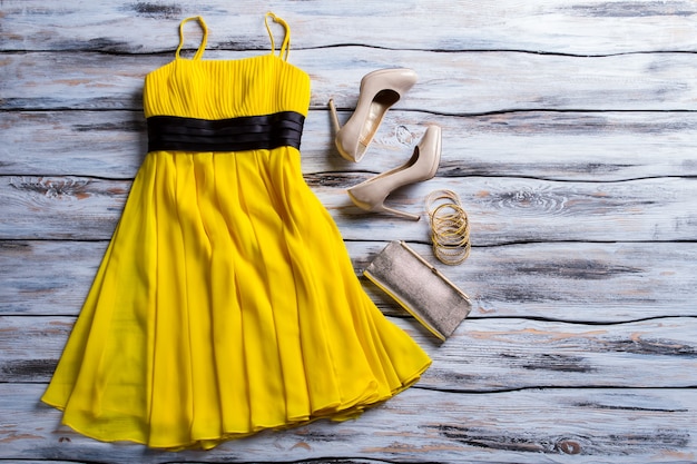 Yellow dress, purse and shoes. Casual yellow dress with accessories. Lady&#39;s charming summer outfit. New clothes and heel shoes.