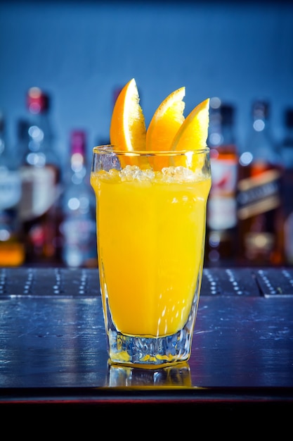 Yellow drink cocktail with orange slices at the bar counter.