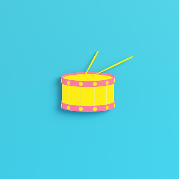 Yellow drum with drum sticks on bright blue background in pastel colors