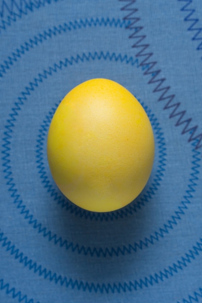 Photo yellow easter egg on a blue surface