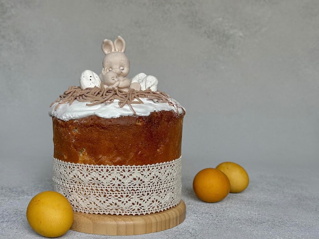 Yellow eggs and a traditional Easter cake with white icing and chocolate hares on a gray background