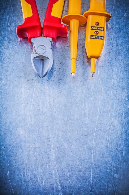 Yellow electrical tester cutting pliers on metallic background electricity concept