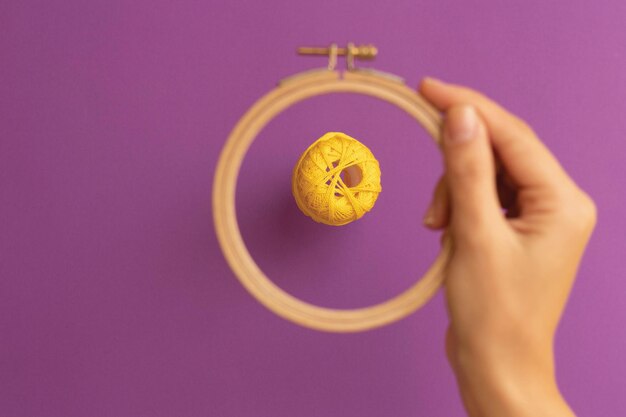 Photo yellow embroidery thread through the embroidery ring on a purple background