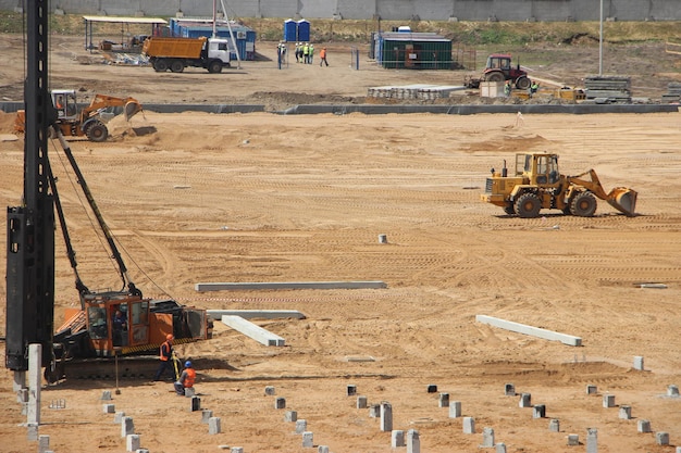 砂利の山に取り組んでいる建設現場の黄色の掘削機