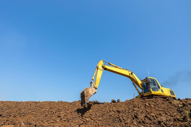 Yellow Excavator digging Digger machine adjusting ground level in construction site