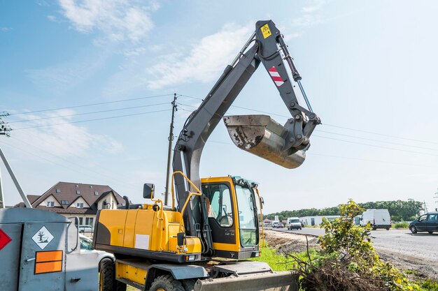 Photo yellow excavator loader standing against sunny cloudy sky during road construction