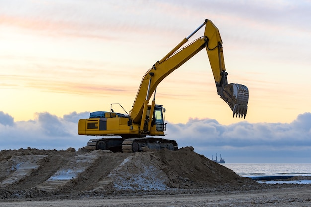 Yellow excavator working on construction site. The road construction.