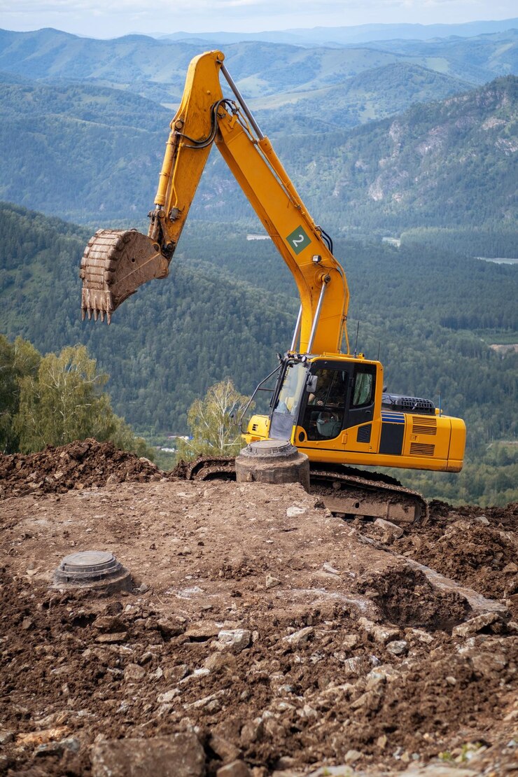A yellow excavator works in the mountains construction of roads