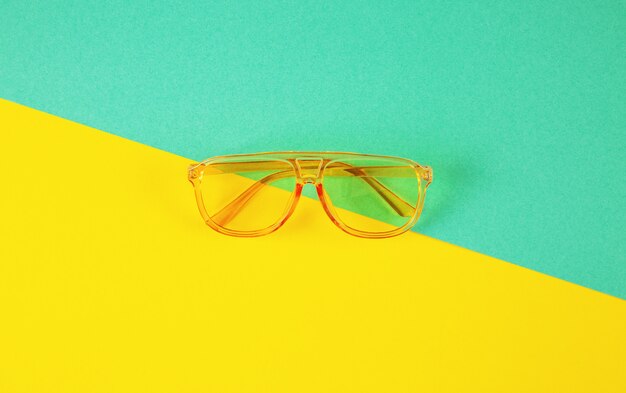 Yellow fahionable sunglasses on abstract color paper background