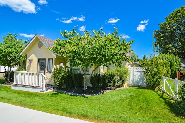 yellow family house with small front yard family house with concrete pathway in front of the entrance on sunny day